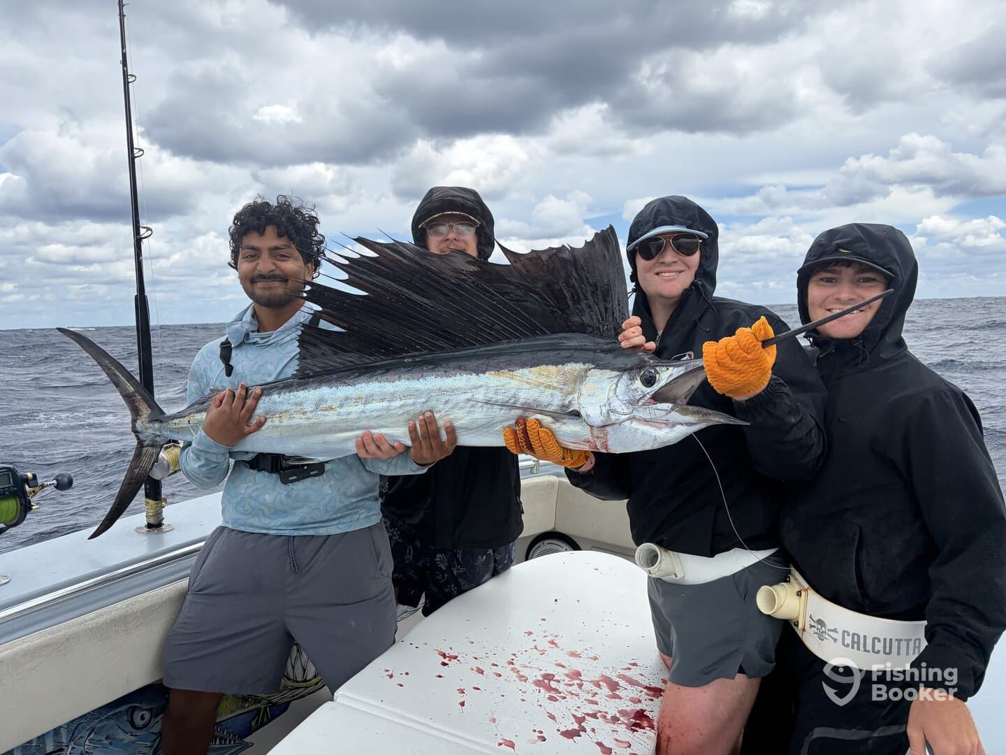 A group of anglers proudly displaying a large Sailfish on a fishing charter, showcasing their successful catch in open waters.