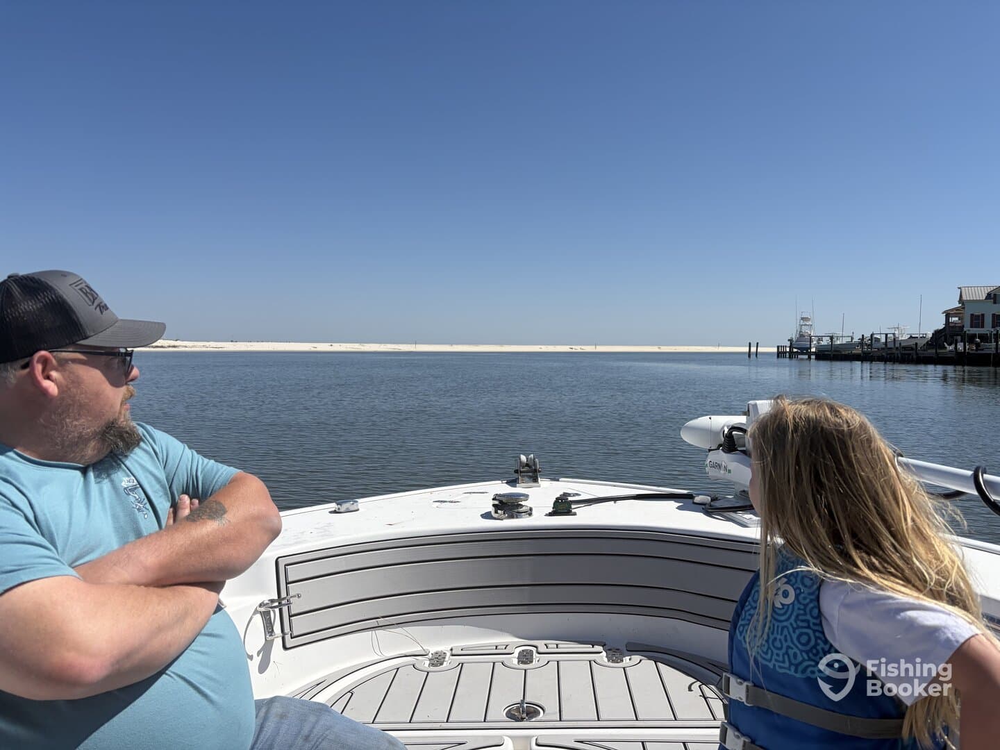 A man and a young girl enjoying a day on a boat, gazing at the serene waters and sandy shorelines, highlighting a family fishing experience.