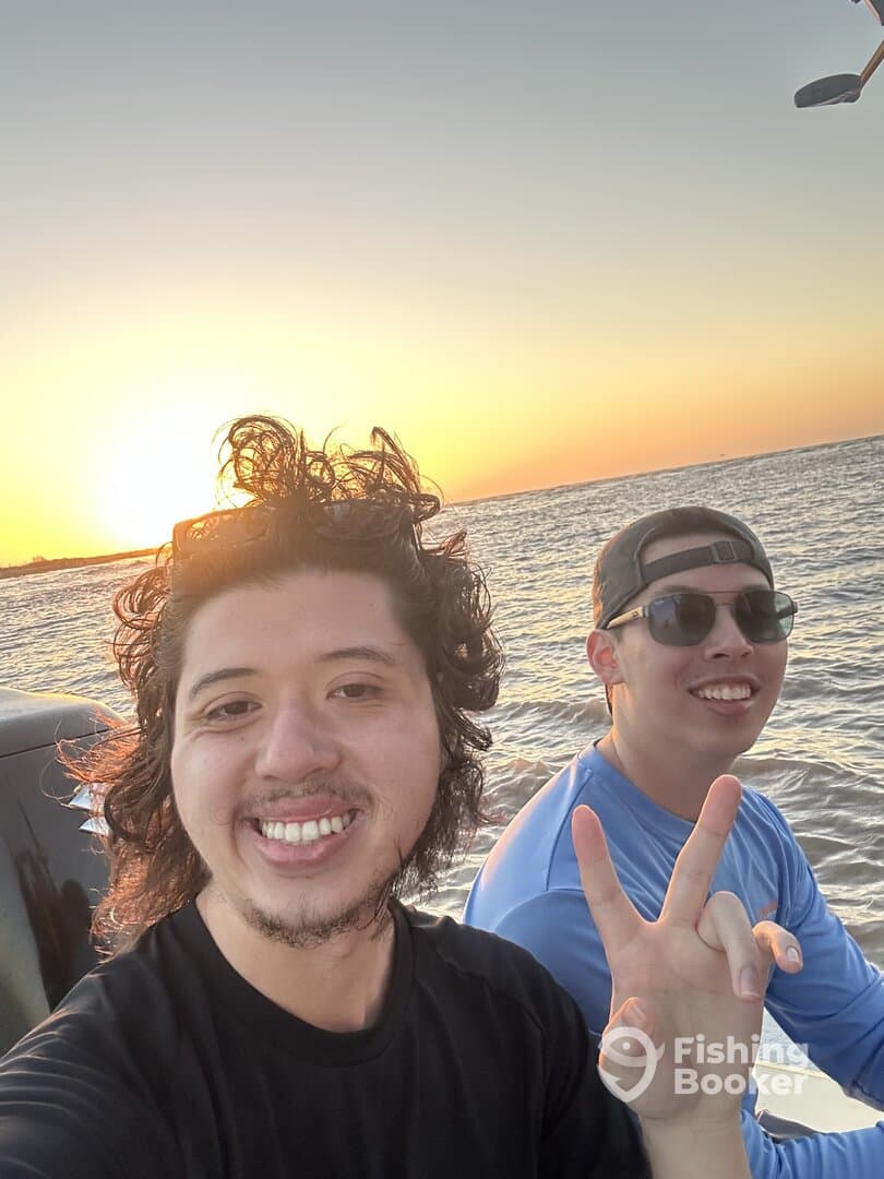 Two anglers enjoying a sunset on the water, capturing a moment of camaraderie during their fishing trip.