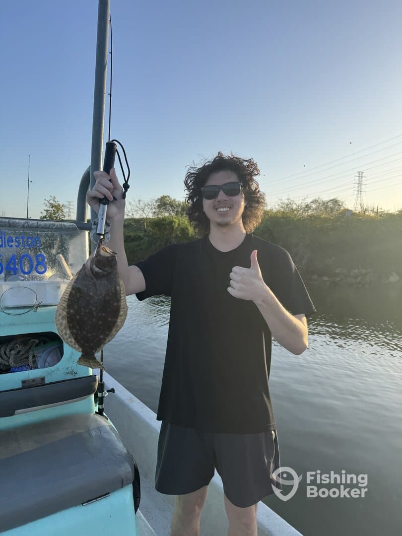 Angler proudly displaying a Flounder while giving a thumbs up on a fishing trip.