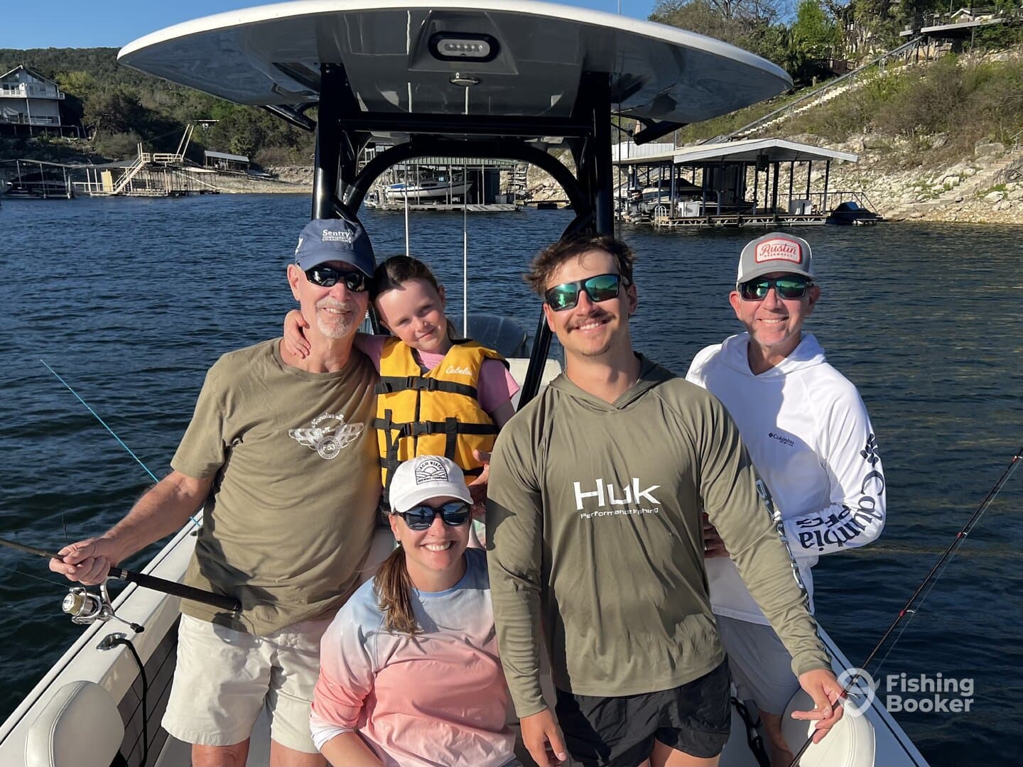 A family group poses together on a boat, enjoying a day of fishing on a scenic lake.