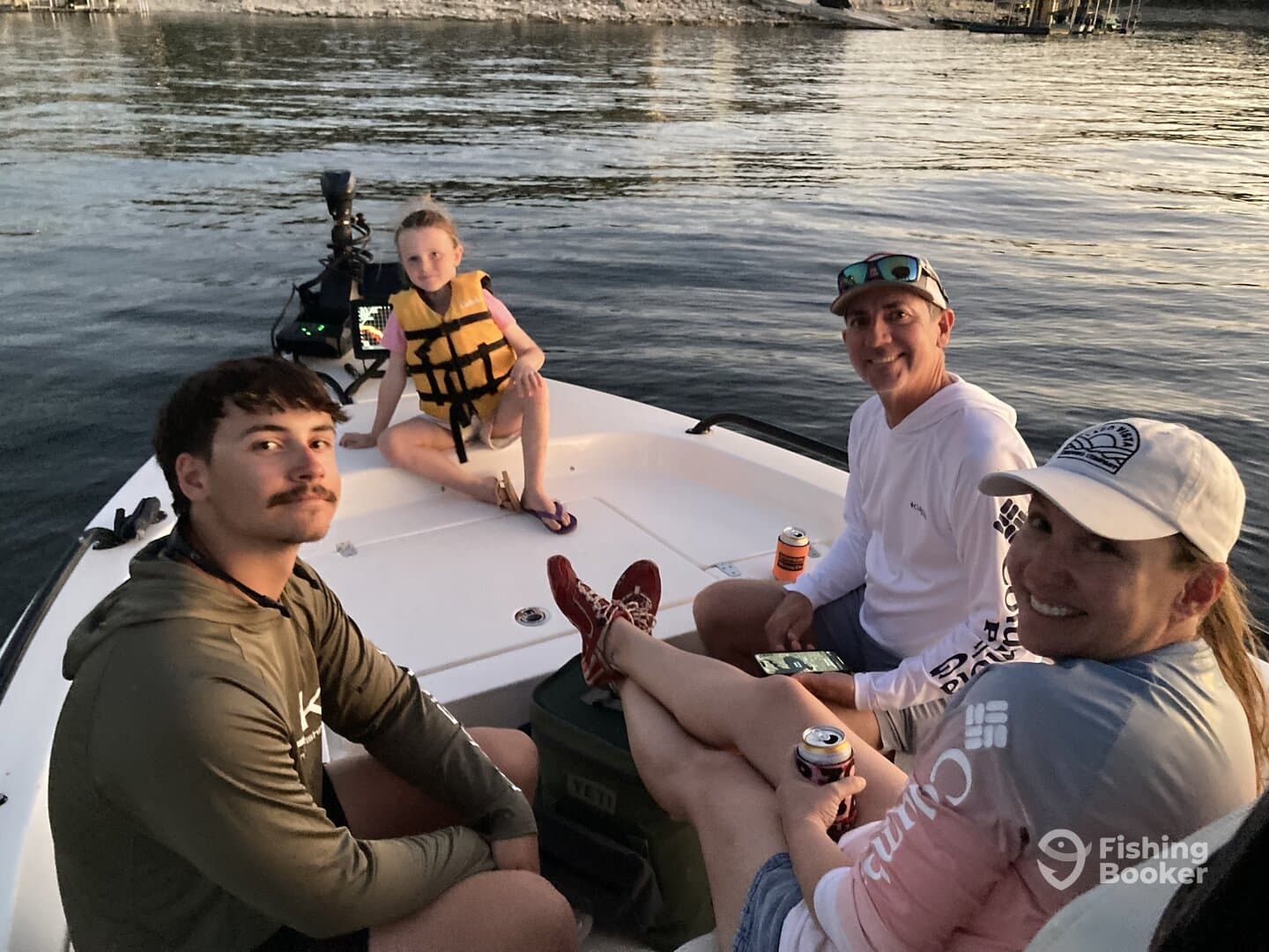 A family enjoying a relaxing moment on a boat, with a young girl in a life jacket and adults seated comfortably, showcasing a casual fishing trip atmosphere.