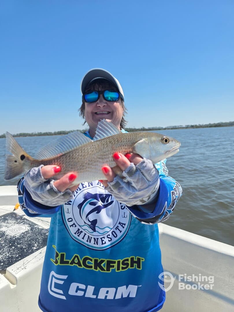 A proud angler holding a Redfish while enjoying a sunny day on the water.
