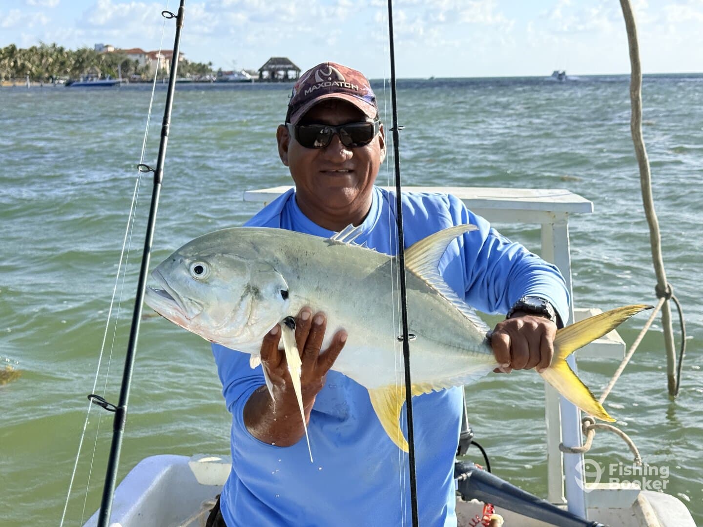 Angler proudly displaying a large Jack Crevalle while fishing from a boat in a sunny coastal environment.