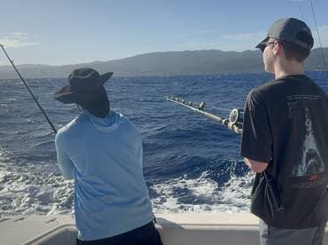 Two anglers casting lines while deep-sea fishing in a scenic ocean setting, showcasing the excitement of the sport.