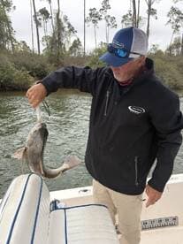 An angler proudly displaying a large fish while on a fishing charter, surrounded by a scenic waterway.