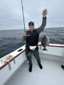 An angler proudly displaying a freshly caught fish while fishing on a boat in open waters.