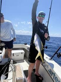 A young angler proudly displaying a colorful fish while fishing on a charter boat in open waters.