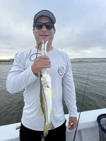 Angler proudly displaying a Snook caught while fishing from a boat in a coastal waterway.