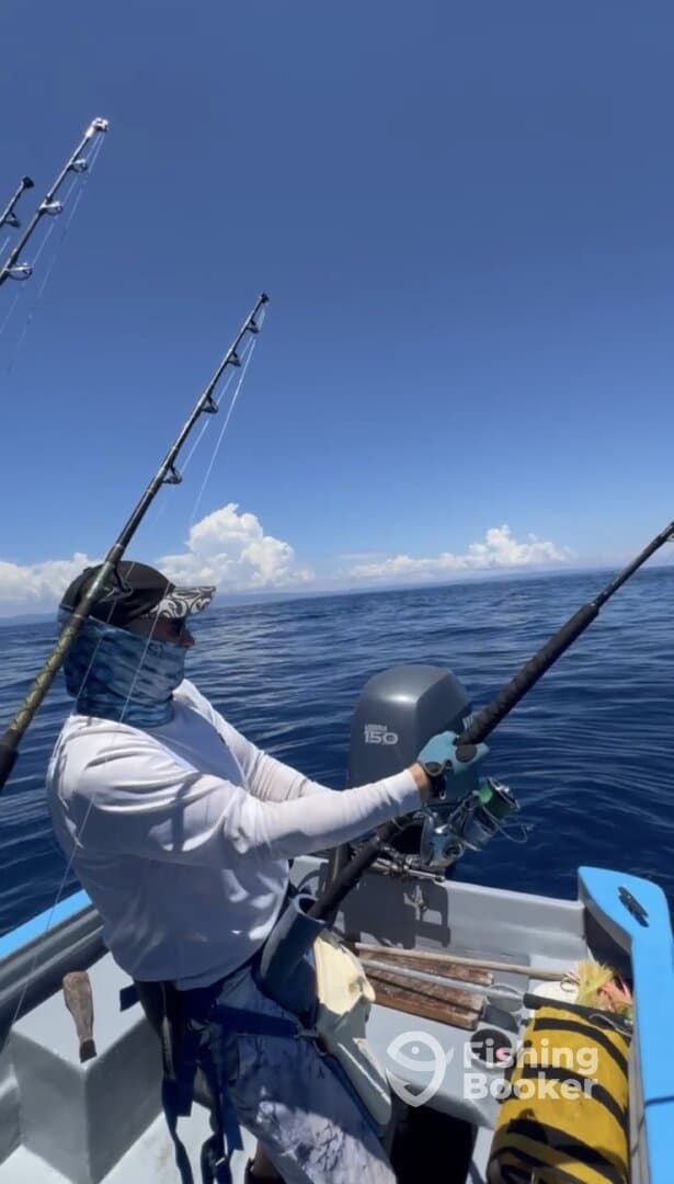 Angler actively reeling in a catch while fishing on a calm day in open waters, showcasing the excitement of sport fishing.