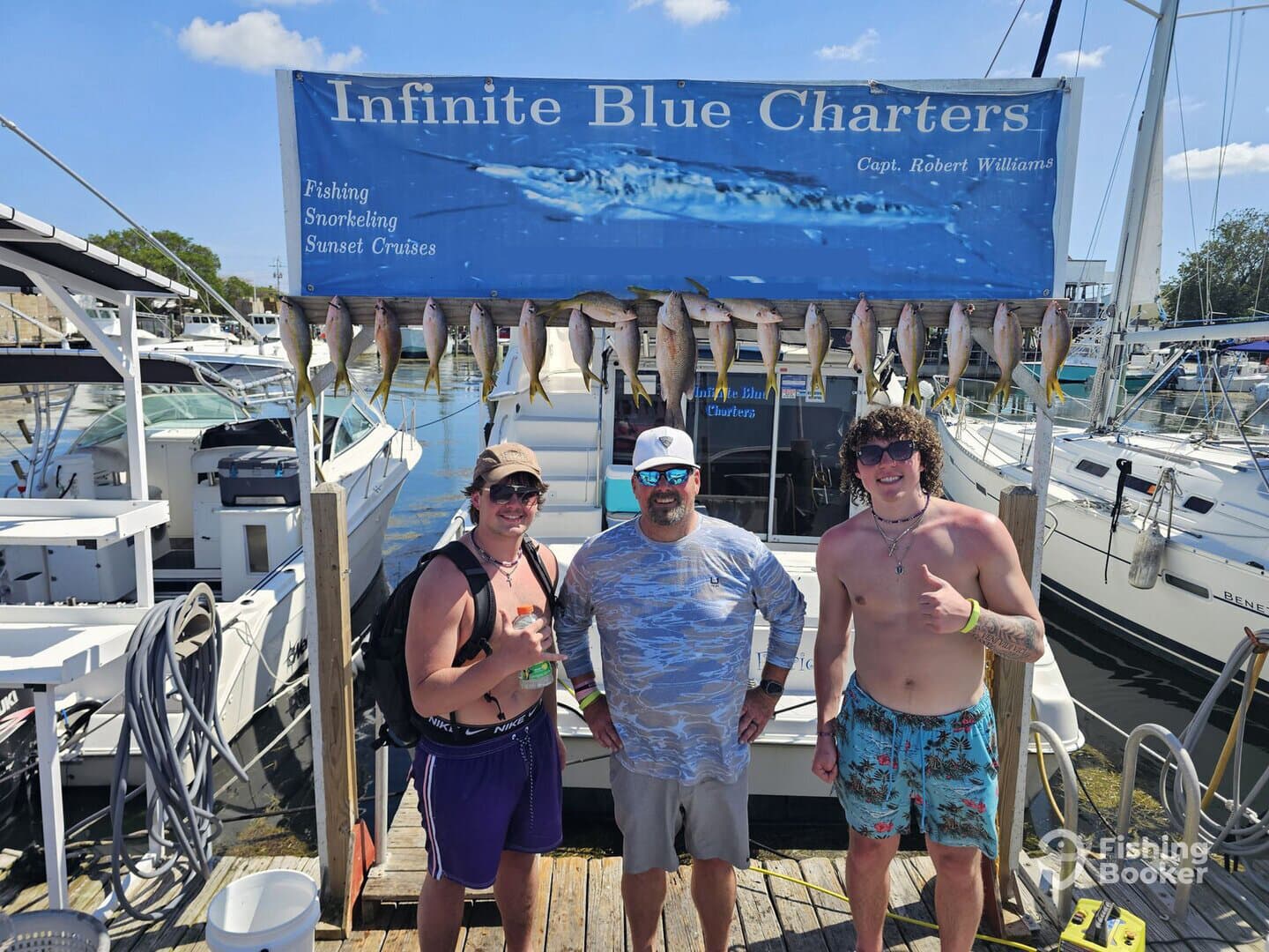 Two anglers proudly posing in front of a catch board displaying a variety of fish after a successful fishing trip with Infinite Blue Charters.