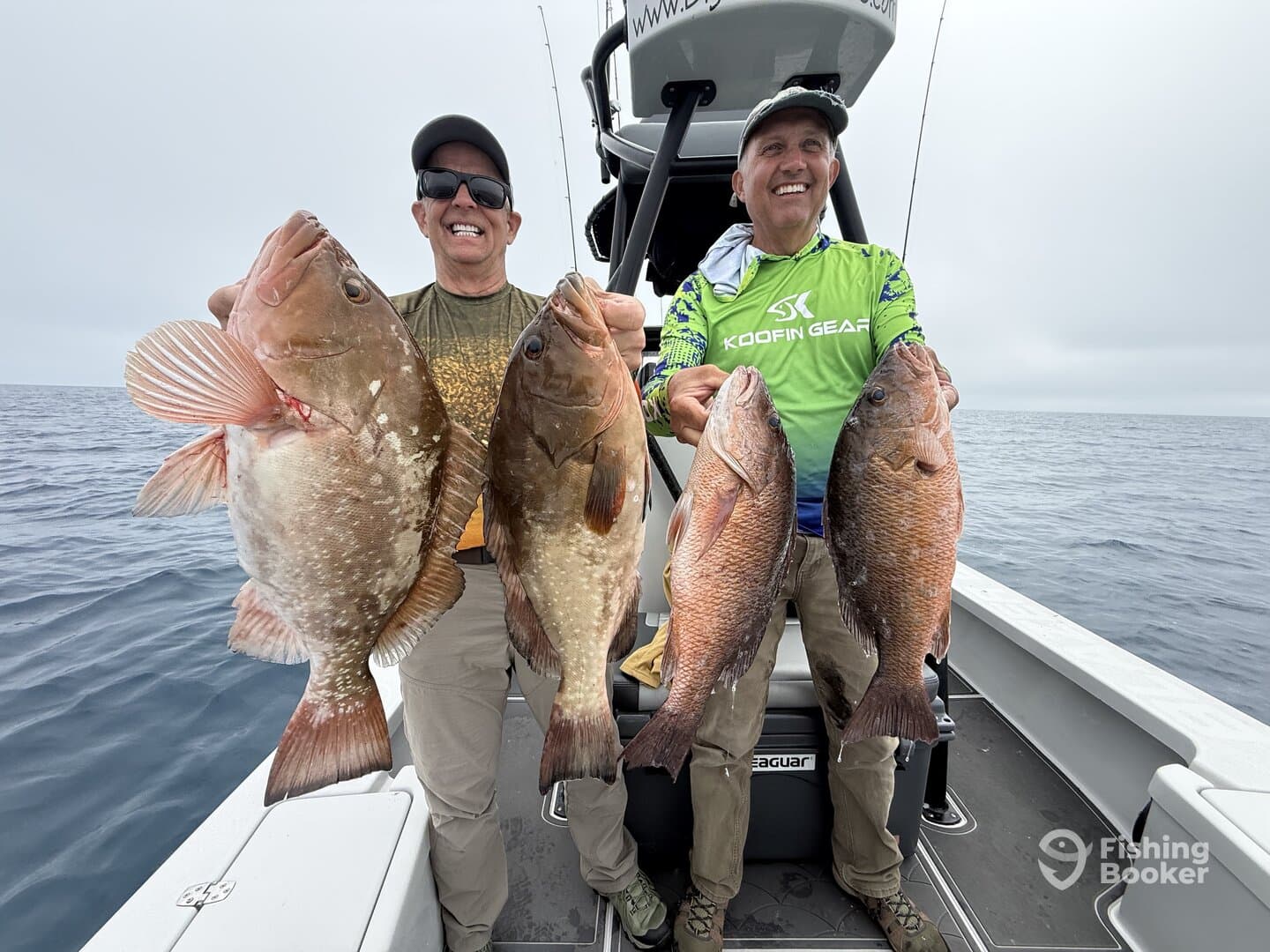Two anglers proudly displaying their catch of Grouper and Snapper while fishing offshore.