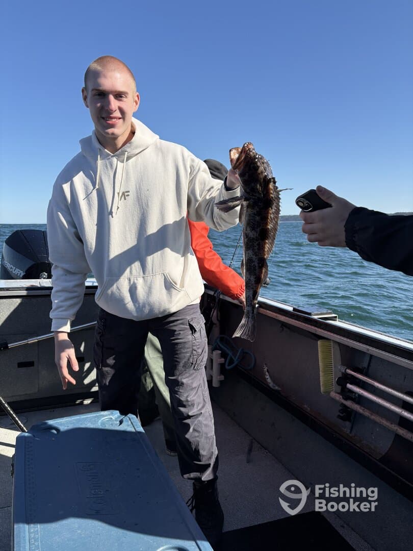 A young angler proudly displaying a large fish on a boat during a fishing trip.