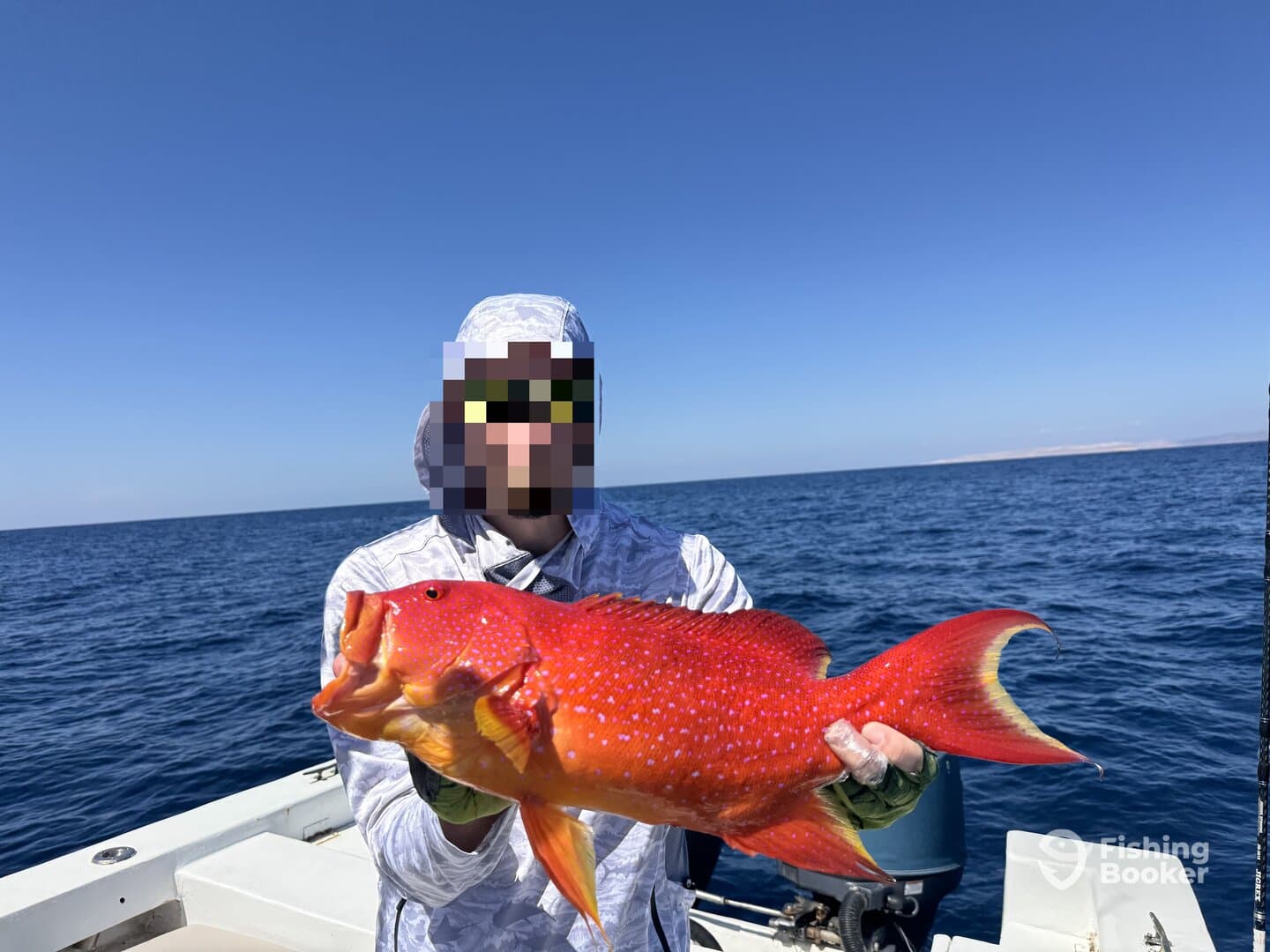 Angler proudly displaying a vibrant Red Snapper while fishing offshore, showcasing the beautiful blue ocean backdrop.