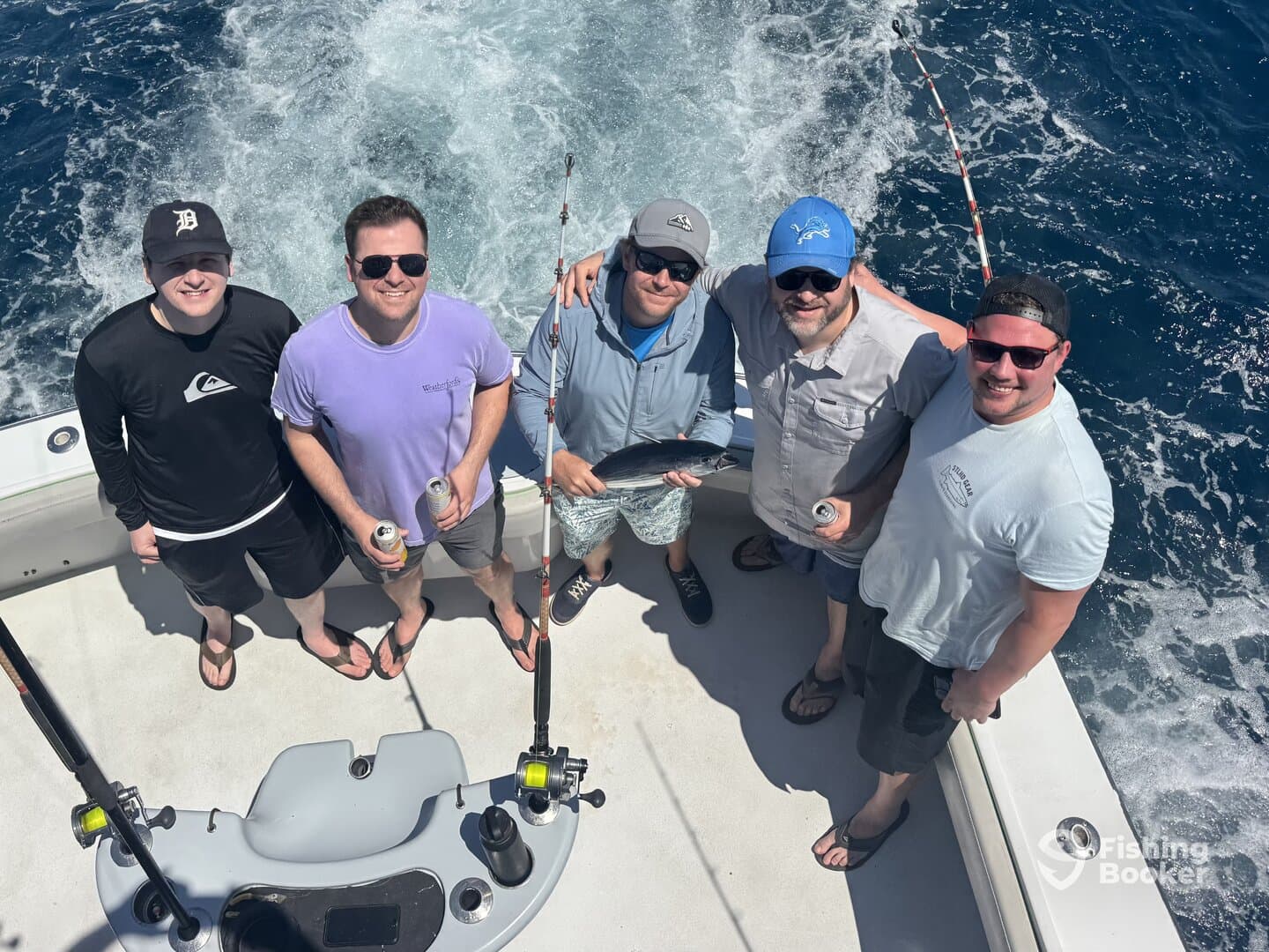 A group of friends enjoying a day of fishing on a boat, proudly displaying their catch while surrounded by the beautiful ocean backdrop.