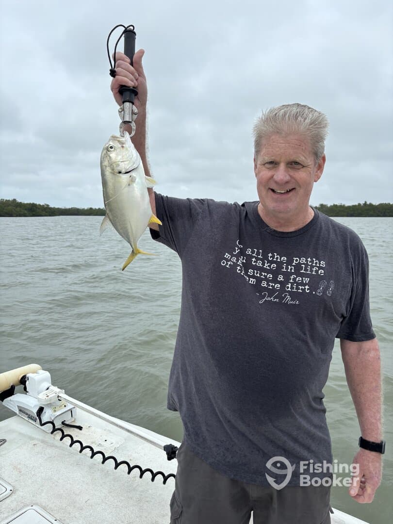 Angler proudly displaying a caught fish while fishing on a boat in a coastal environment.