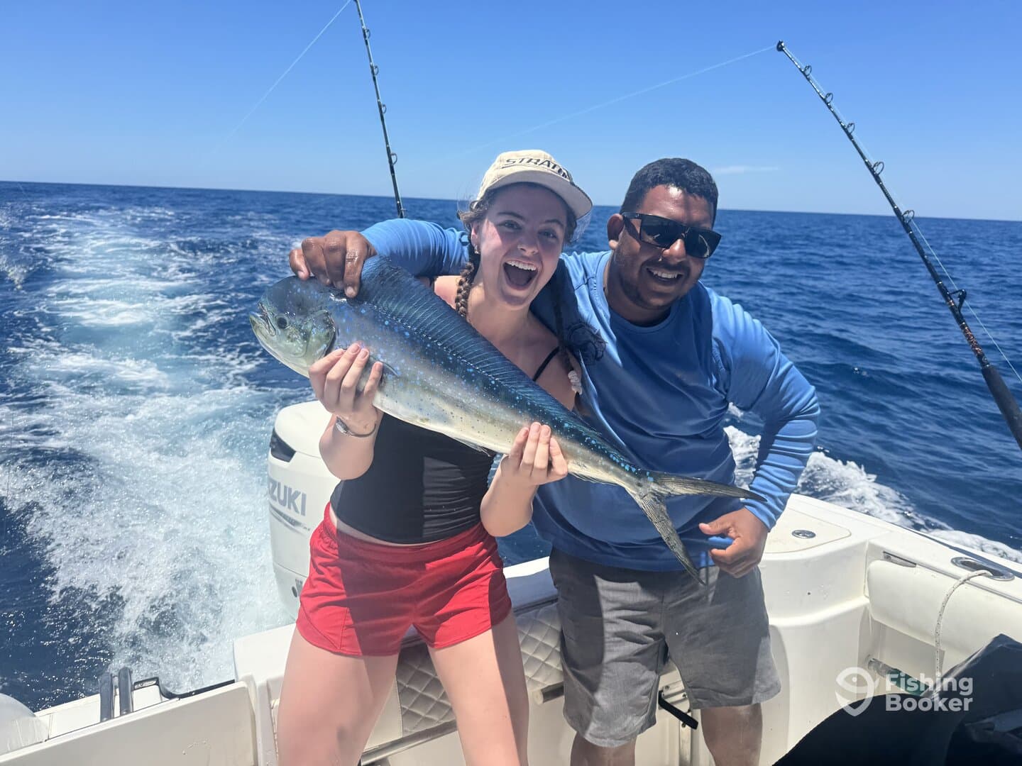 A young angler joyfully displays a vibrant Mahi-Mahi while fishing on a boat, showcasing a successful day on the water.