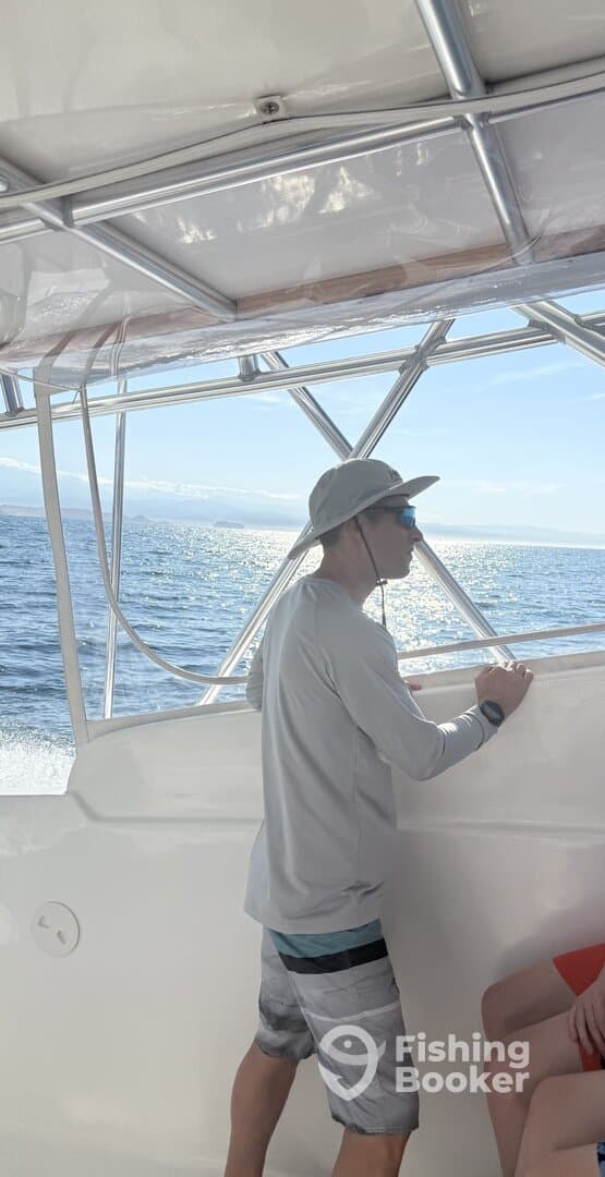 A young angler enjoying the view from inside the boat while out on the water, showcasing a relaxed fishing atmosphere.