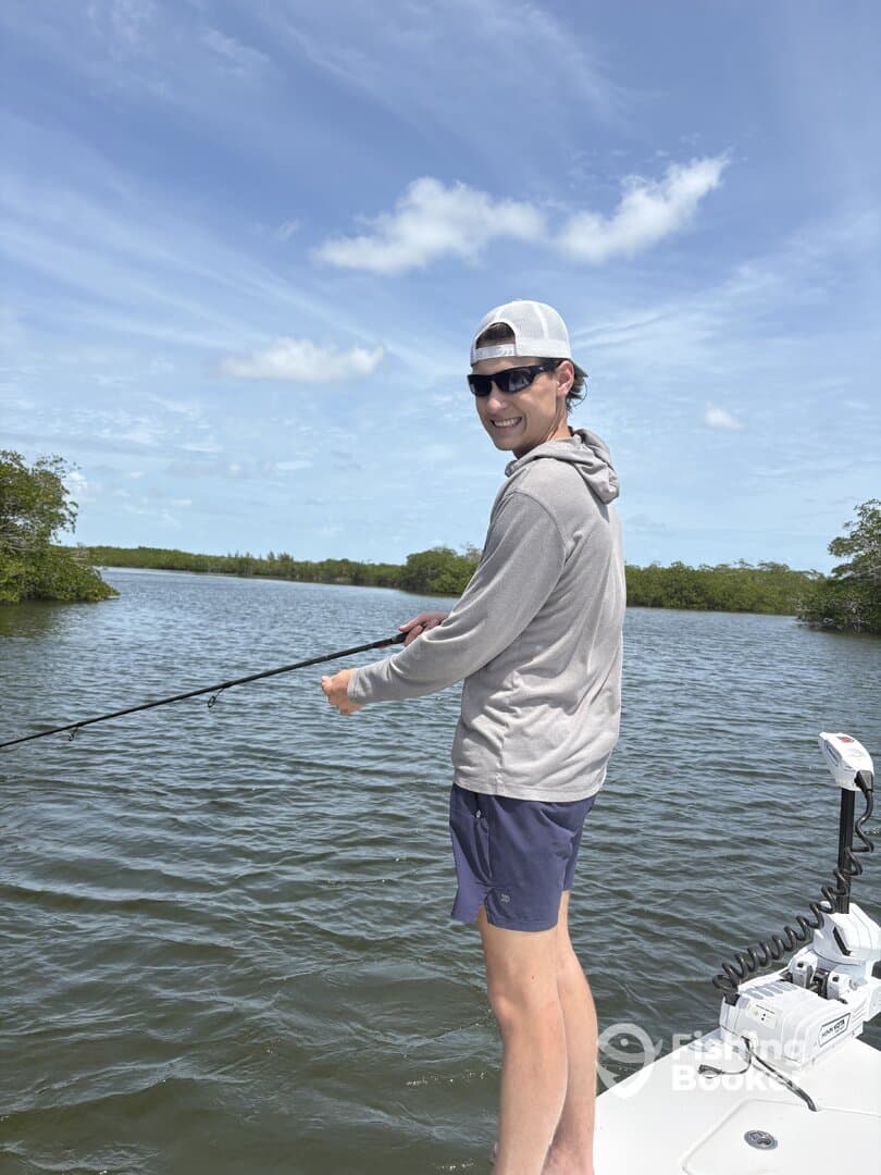 A young angler casting a line while fishing in a scenic mangrove area, showcasing the excitement of the sport.