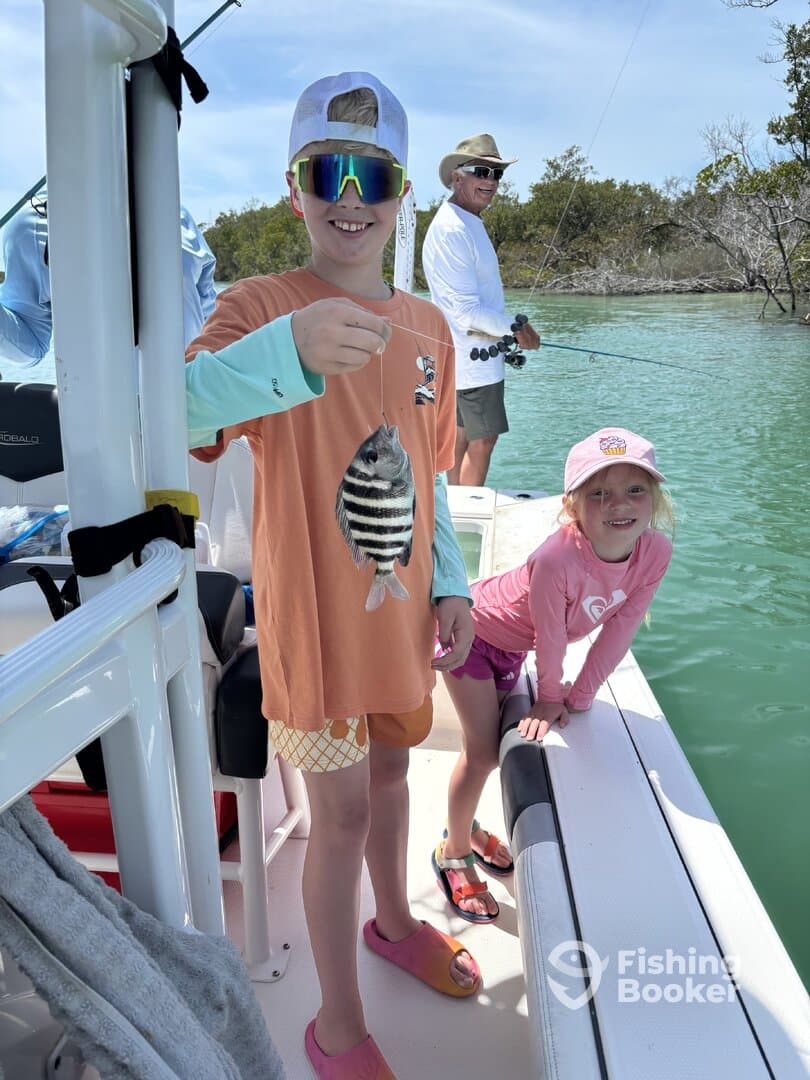 A young angler proudly displaying a striped fish while fishing with family on a boat in a scenic waterway.