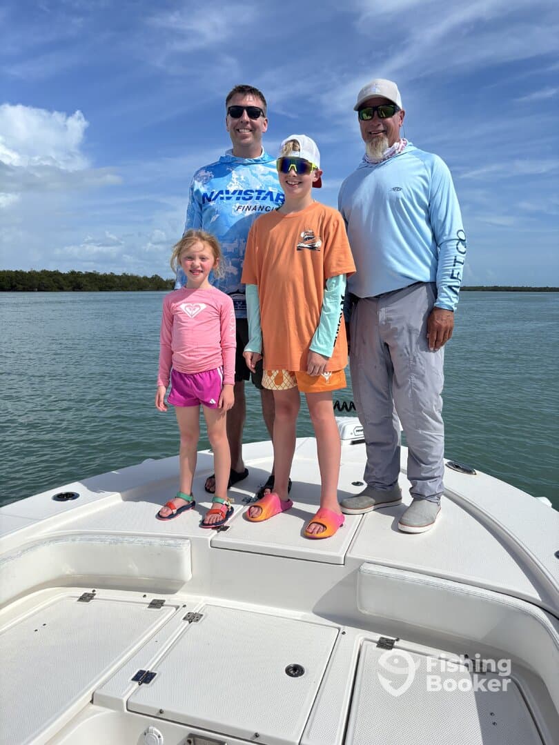 A family of four enjoying a day on a boat in a scenic fishing environment, with clear skies and calm waters.