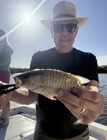 An angler proudly displaying a freshly caught fish while enjoying a sunny day on the water.