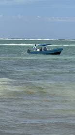 A small fishing boat navigating through clear waters, with a group of anglers onboard enjoying a day of fishing.