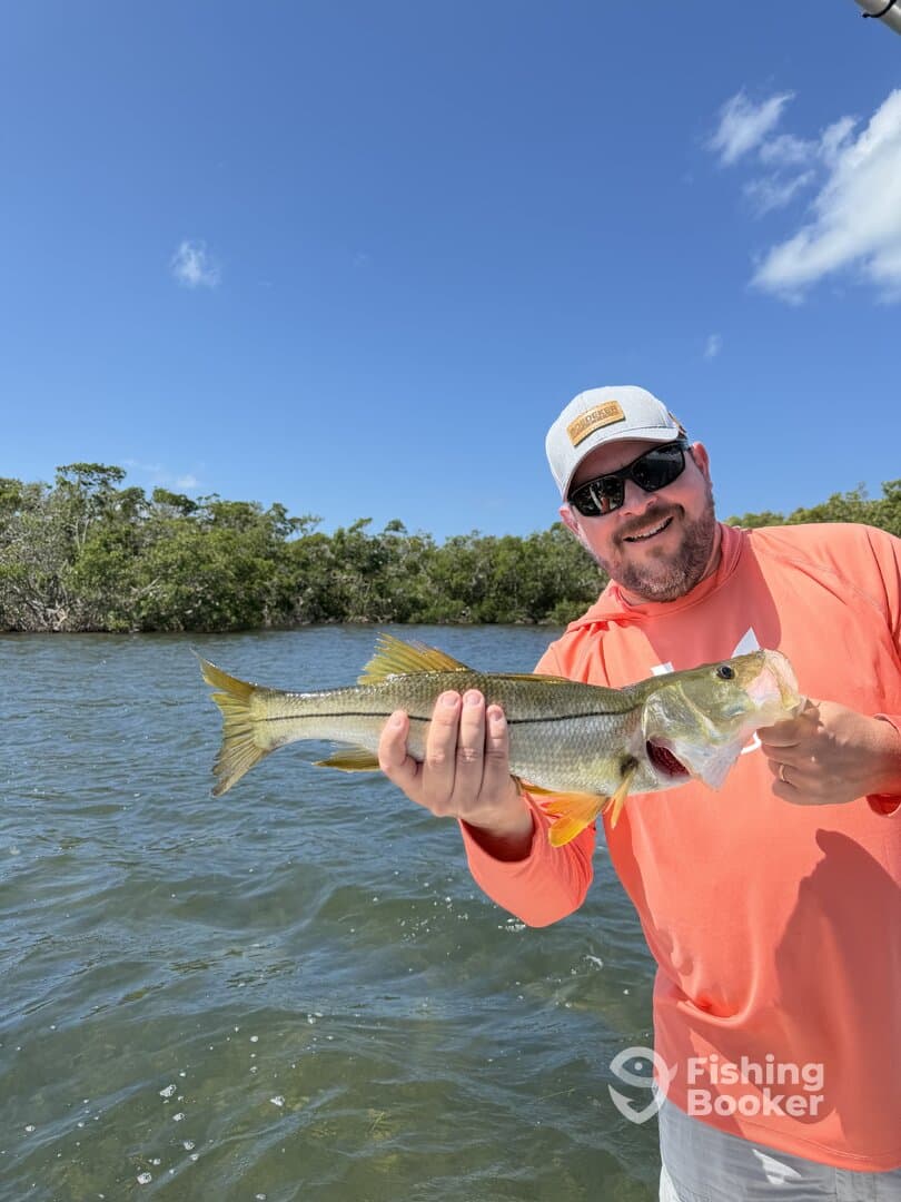 Angler proudly displaying a Snook caught while fishing in a coastal waterway.