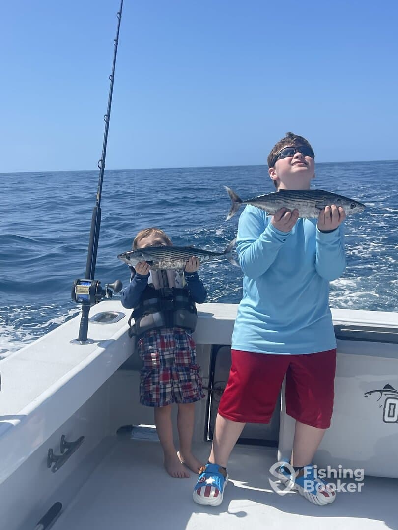 Two young anglers proudly displaying their catch of Spanish Mackerel while enjoying a day of fishing on the open sea.