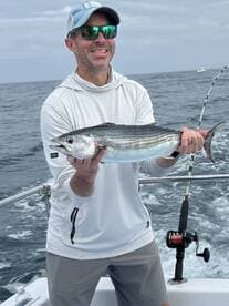 Angler proudly displaying a caught fish while aboard a fishing boat in open waters.