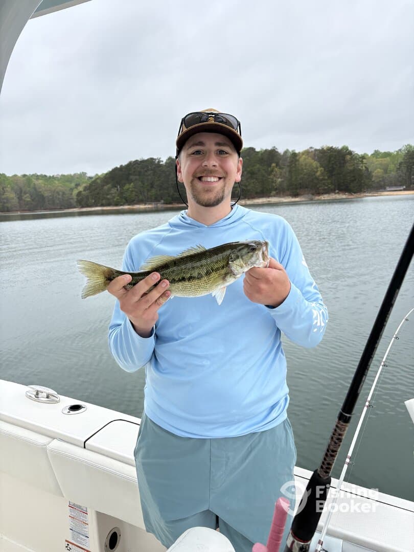 Angler proudly displaying a large Largemouth Bass while fishing on a serene lake.