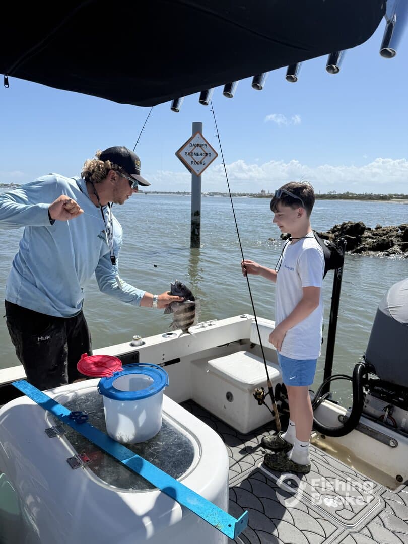 A young angler excitedly watches as an adult holds up a freshly caught fish aboard a boat, enjoying a day of fishing in a coastal environment.