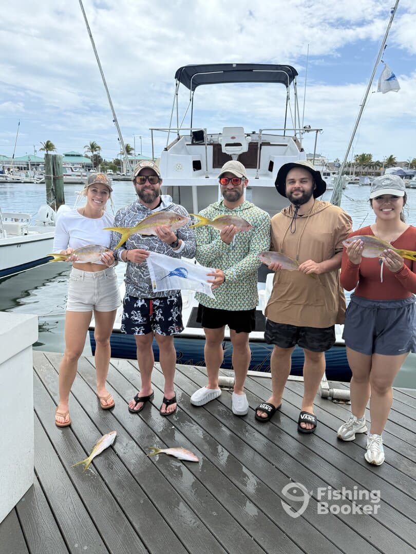 A group of five anglers proudly displaying their catch of Yellowtail Snapper at the dock after a successful fishing trip.