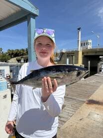 Young angler proudly holding a large fish at the dock, showcasing a successful fishing trip.