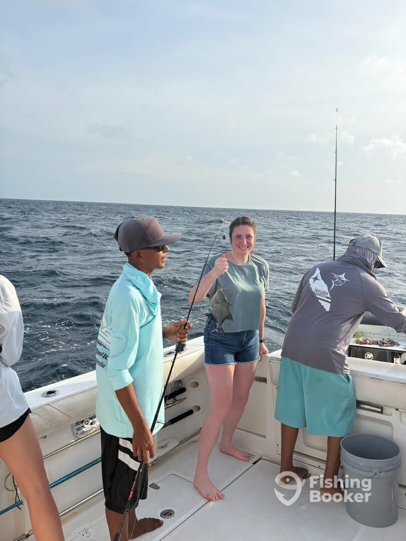 A young angler and a friend proudly display their catch on a fishing trip, showcasing a colorful fish against the backdrop of the open sea.
