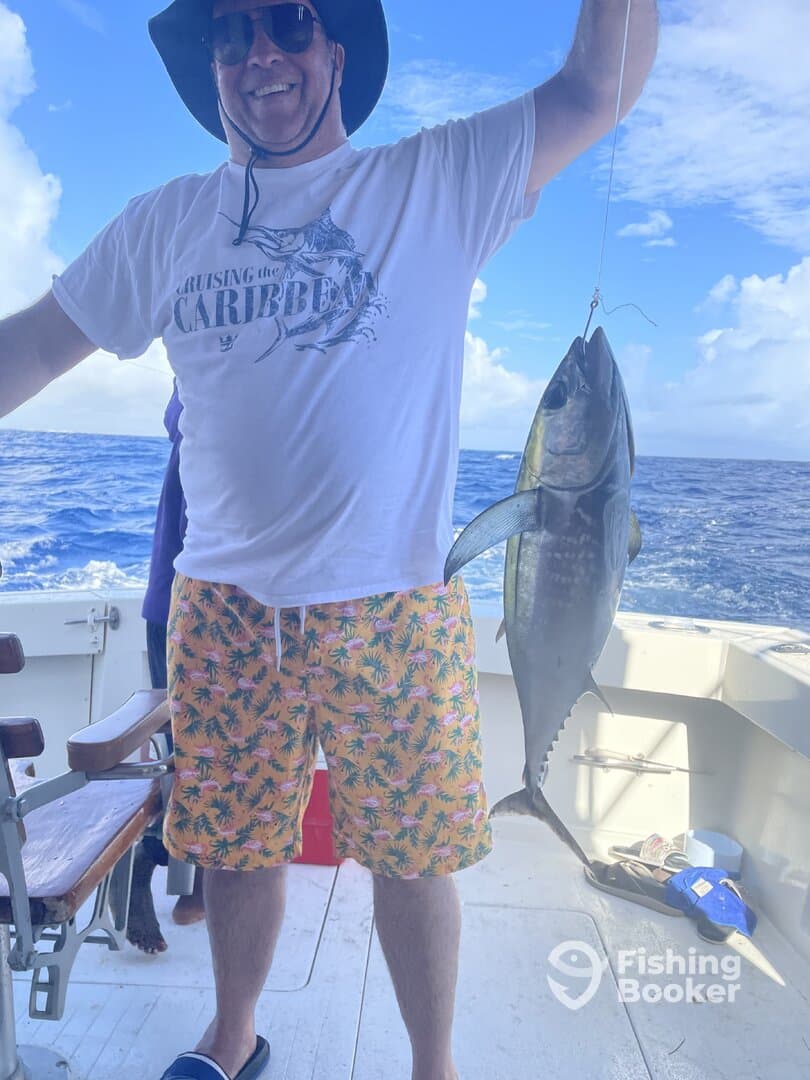 A proud angler displays a large fish while fishing in the Caribbean, showcasing a vibrant atmosphere and a successful catch.