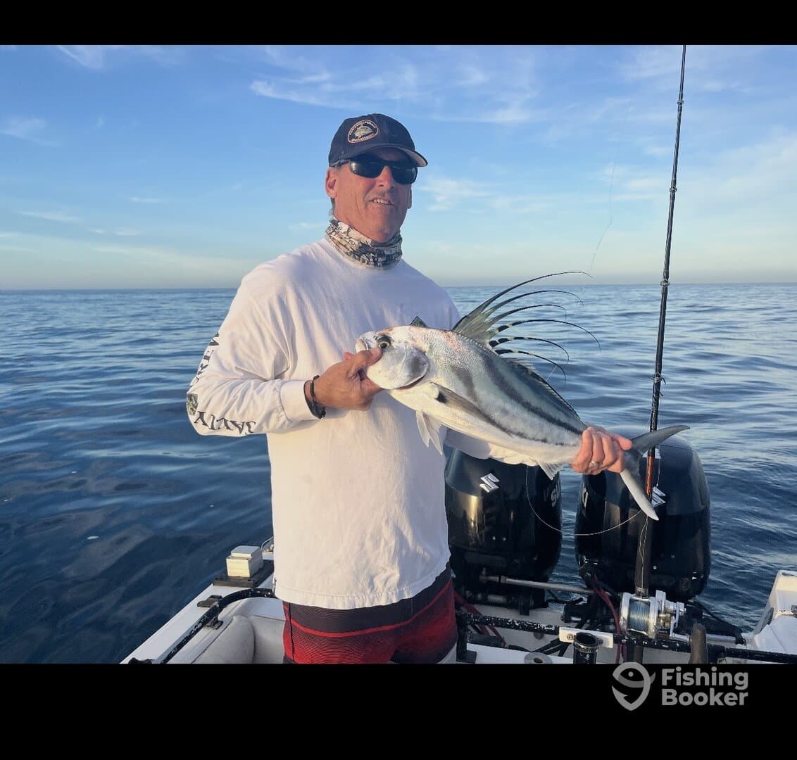 Angler proudly displaying a beautiful Roosterfish while fishing in open waters.