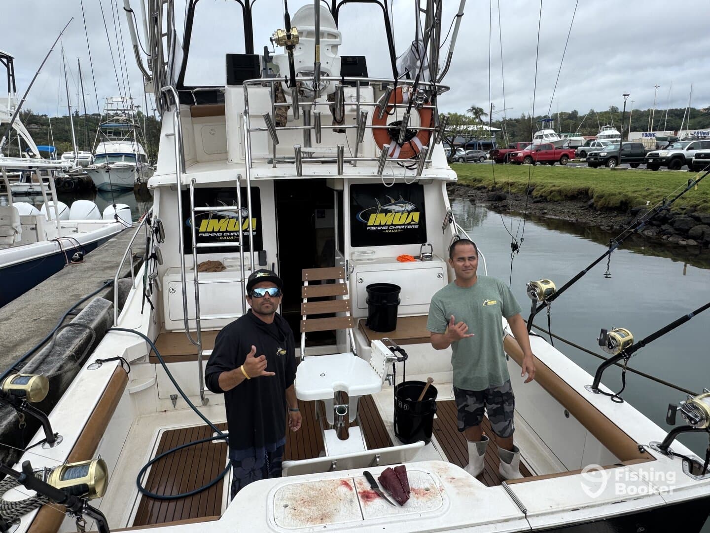 Two crew members aboard a fishing charter boat, showcasing the interior setup with fishing gear and a cleaning station.