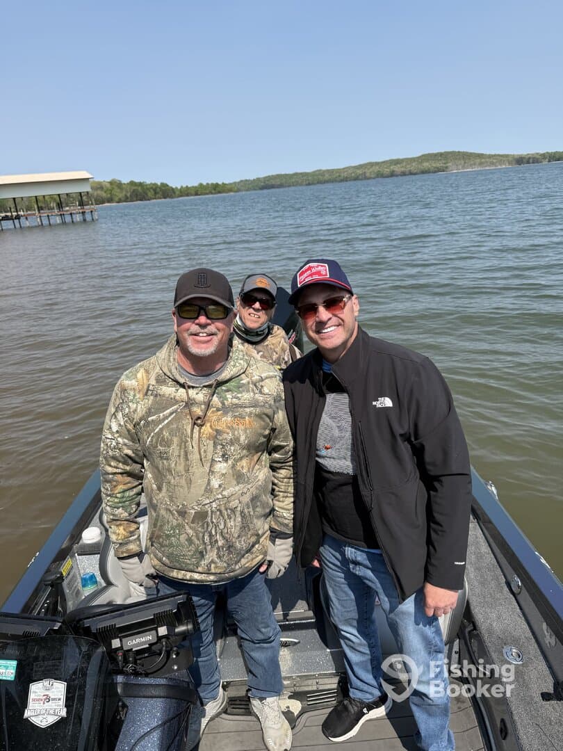 A group of anglers enjoying a day on the water, smiling aboard a fishing boat with a scenic backdrop.