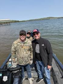 A group of anglers enjoying a day on the water, smiling aboard a fishing boat with a scenic backdrop.
