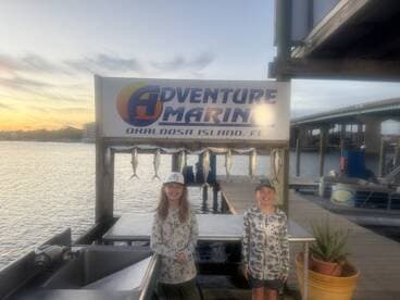 Two young anglers proudly posing in front of a catch board displaying several Spanish Mackerel at Adventure Marina in Okaloosa Island, FL.