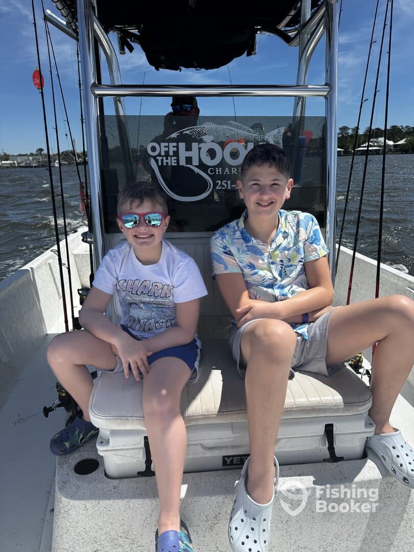 Two young anglers enjoying a day on the water aboard a charter boat, showcasing a fun and relaxed atmosphere.
