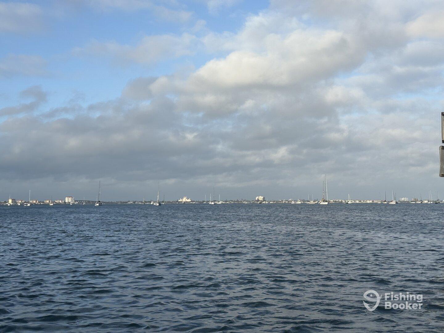 A scenic view of the water with sailboats in the distance, capturing the tranquil atmosphere of a fishing environment.