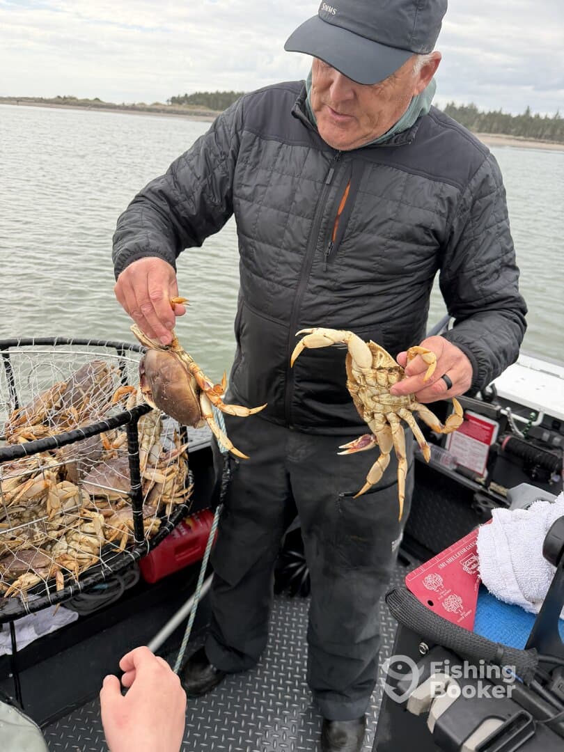 An angler displaying freshly caught crabs while on a fishing boat, showcasing the excitement of crabbing in a coastal environment.