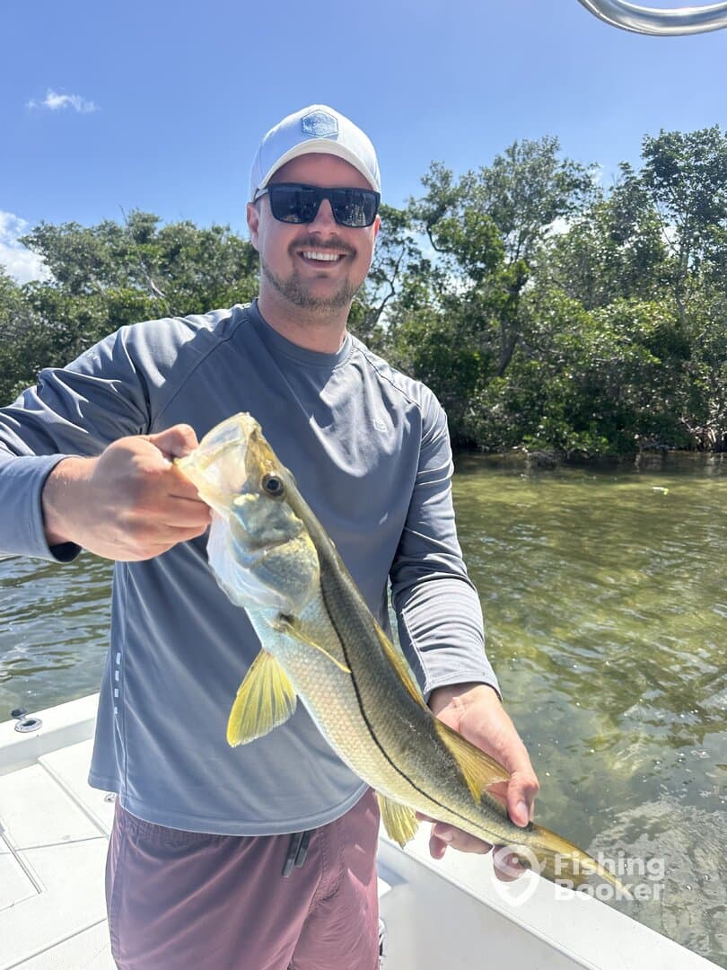 Angler proudly displaying a Snook while fishing in a scenic coastal environment.