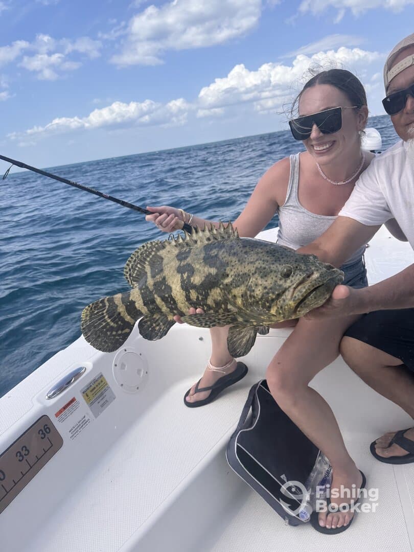 Anglers proudly displaying a large Grouper while fishing in open waters.