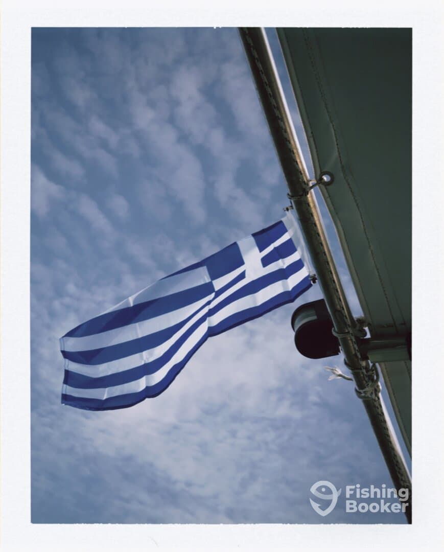 A flag waving against a cloudy sky, possibly indicating a fishing charter location.