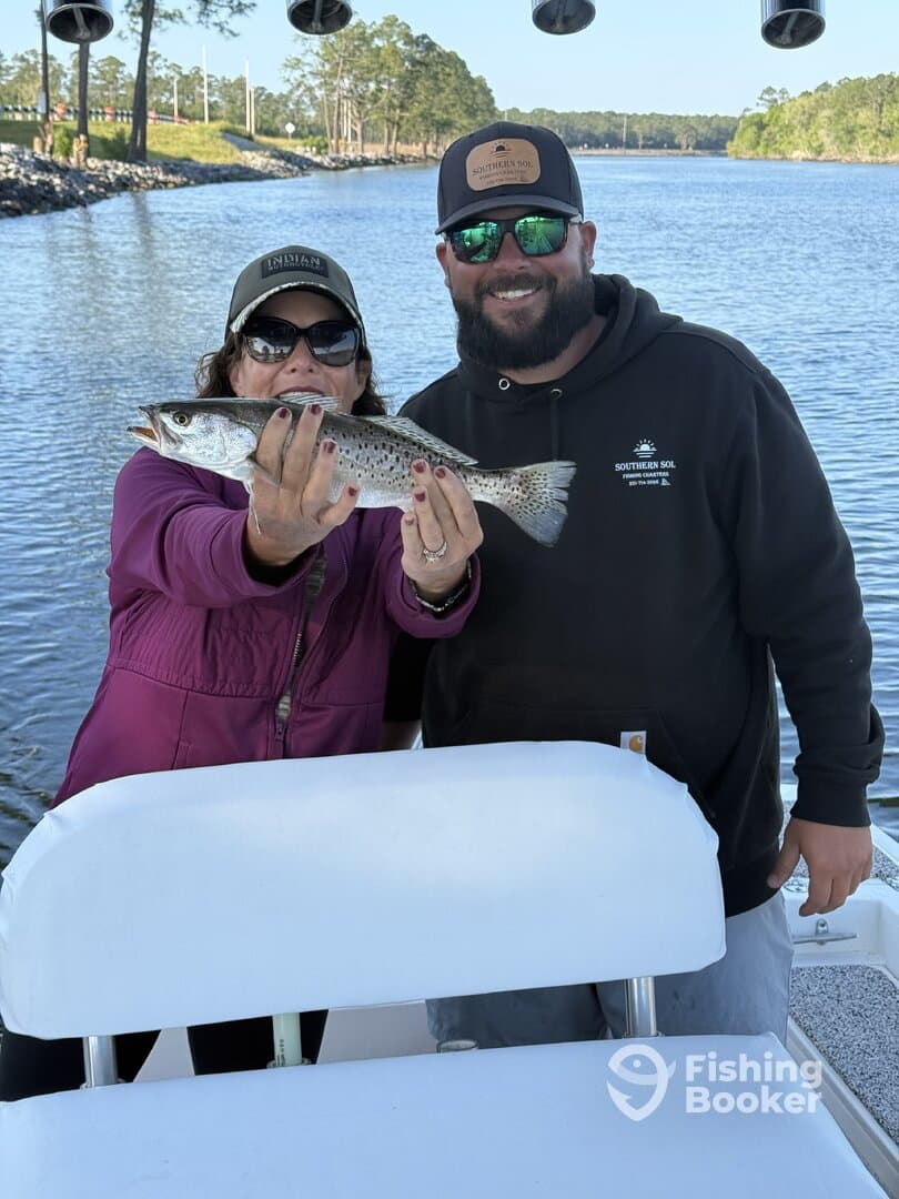 Two anglers proudly displaying a Speckled Trout while enjoying a day on the water.