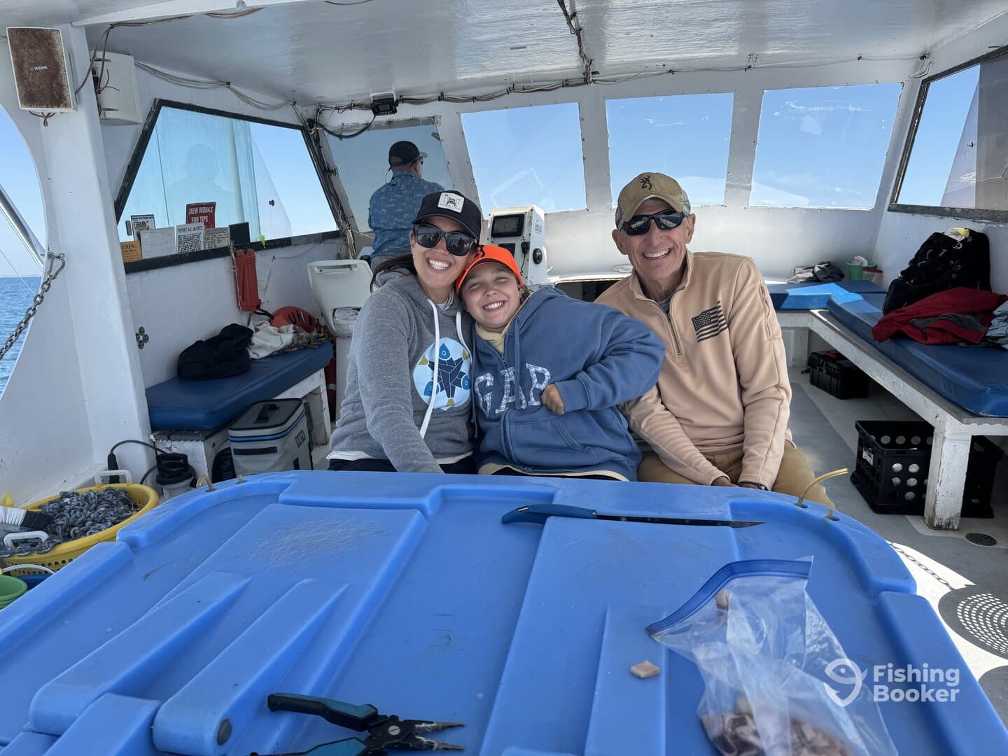 A family enjoying their time aboard a fishing charter, smiling together in the boat's interior.