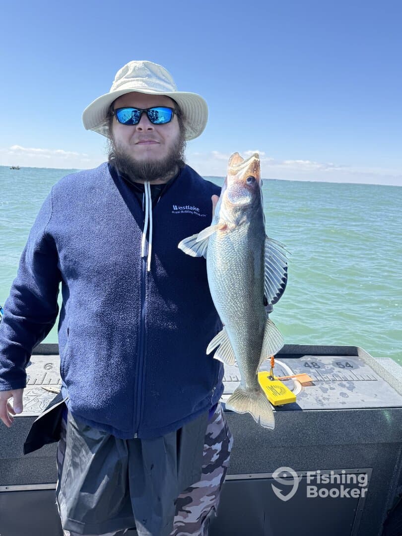 Angler proudly displaying a large Walleye while fishing on a boat, showcasing a beautiful day on the water.